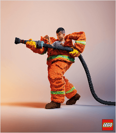 Это фотография из рекламы LEGO, на которой изображен молодой азиатский мальчик в форме пожарного, сделанной из LEGO. Униформа - оранжевая с неоново-зеленой полосой вокруг манжет пальто и брюк. Пожарный стоит одной ногой назад и держит в руке пожарный шланг, тоже сделанный из лего. Голова мальчика появляется из-за верхней части униформы, которая намного больше его и останавливается на плечах. Фотография сделана на однотонном нейтральном фоне. Логотип LEGO отображается в красном поле в правом нижнем углу. Талия Вольф говорит, что LEGO - отличный пример бренда, который использует эмоции в рекламе.