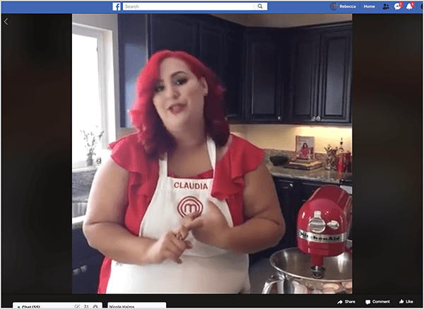 Это скриншот видео в Facebook Live с участием шеф-повара Клаудии Сандовал, которое она провела в 2016 году в рамках перекрестного продвижения с приложением T-Mobile вторники. На видео Клаудия стоит на кухне с черными шкафами и гранитными столешницами. Окно над раковиной пропускает в комнату естественный свет. Клаудия стоит рядом с красным миксером Kitchen Aid. Это латиноамериканка с ярко-рыжими волосами, которые ниспадают чуть ниже плеч. На ней макияж, ярко-красный топ и белый фартук с вышитыми красной нитью логотипом Claudia и логотипом MasterChef. Во время разговора она жестикулирует руками. В 2016 году Стефани Лю вместе с Клаудией сняли это живое видео.
