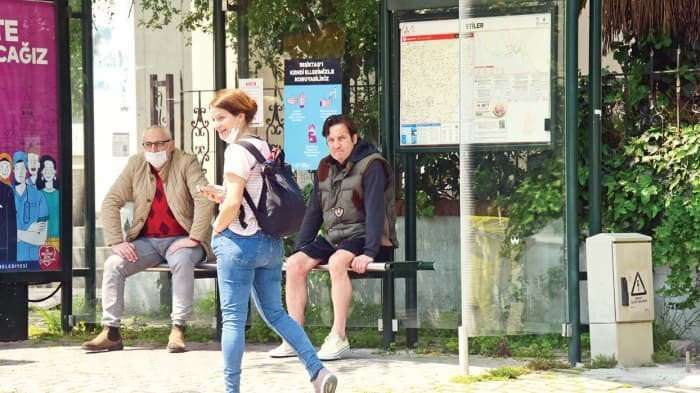 Кая Шилингироглу отображается без маски на автобусной остановке.